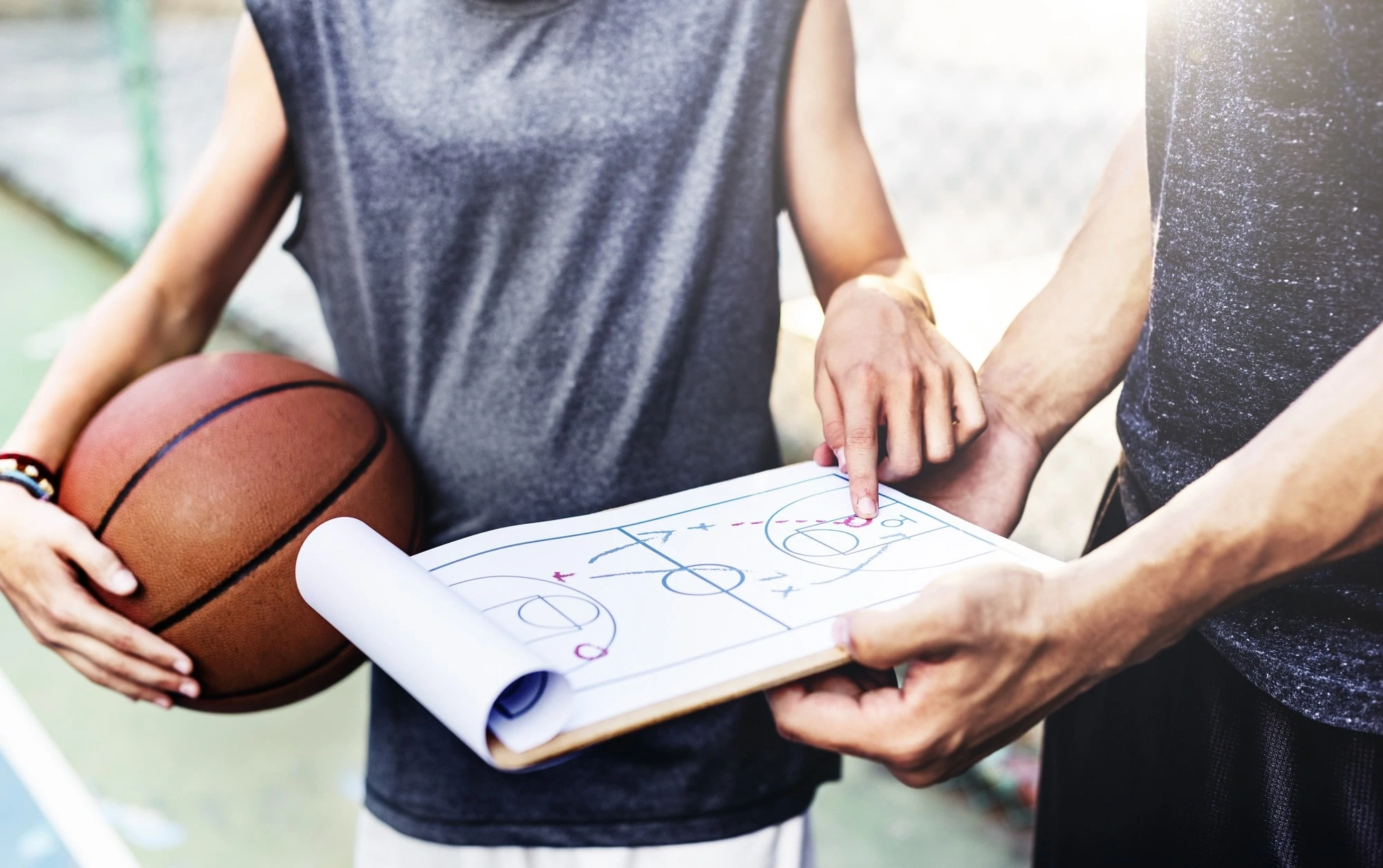 A man with a clipboard talks to a basketball player