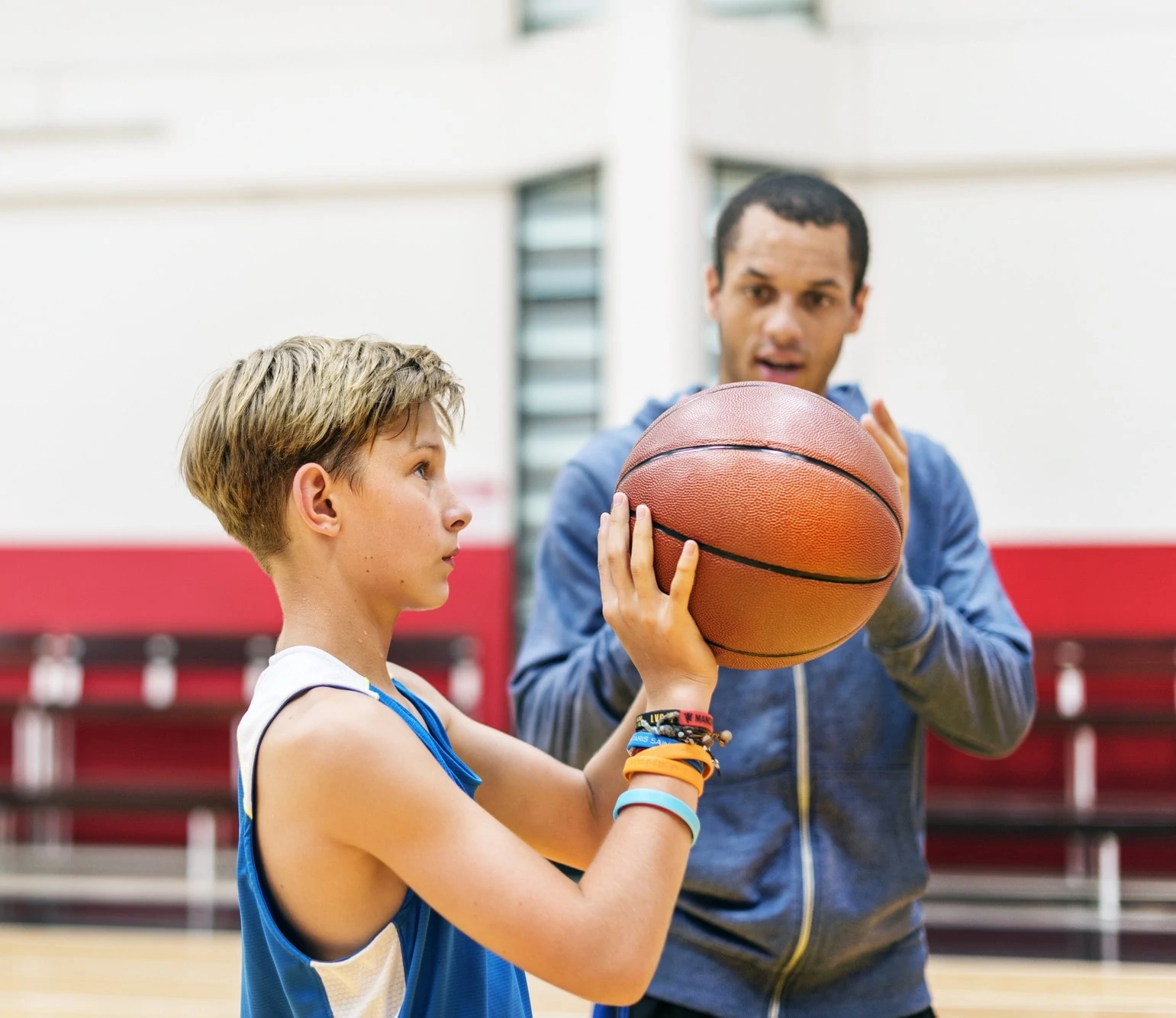 A man and a boy are playing basketball together on a court