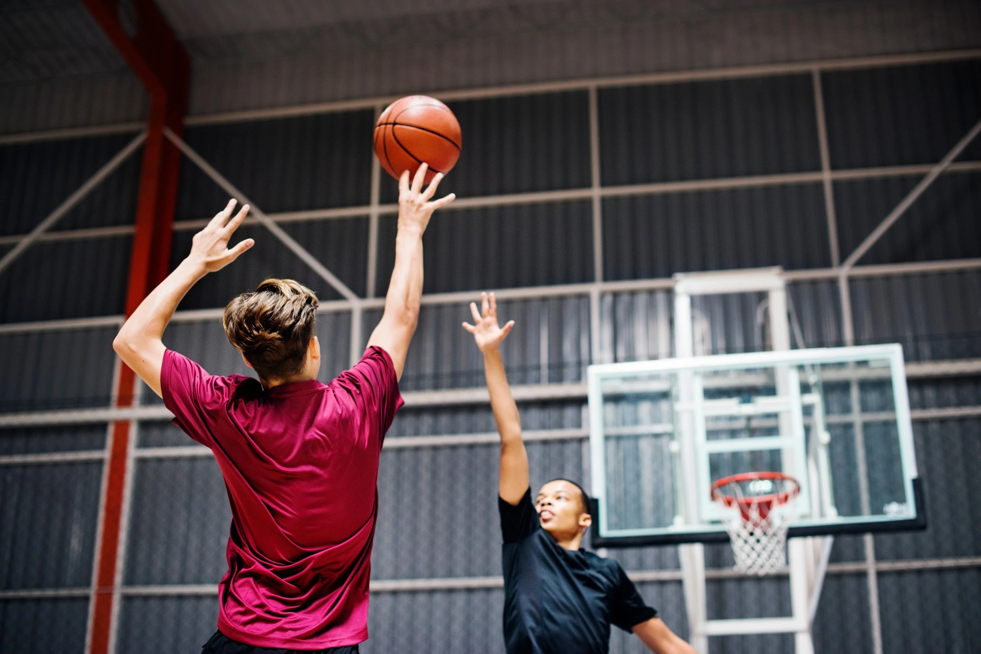 Two men engaged in a basketball game inside a gym