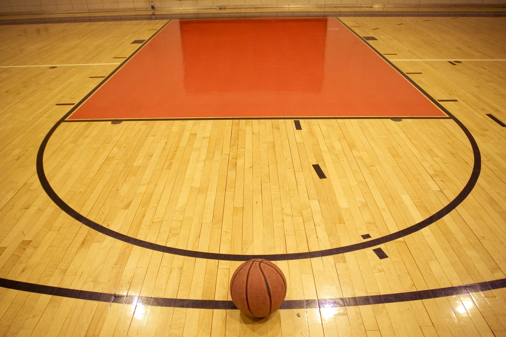 A basketball resting on the court floor inside a gymnasium