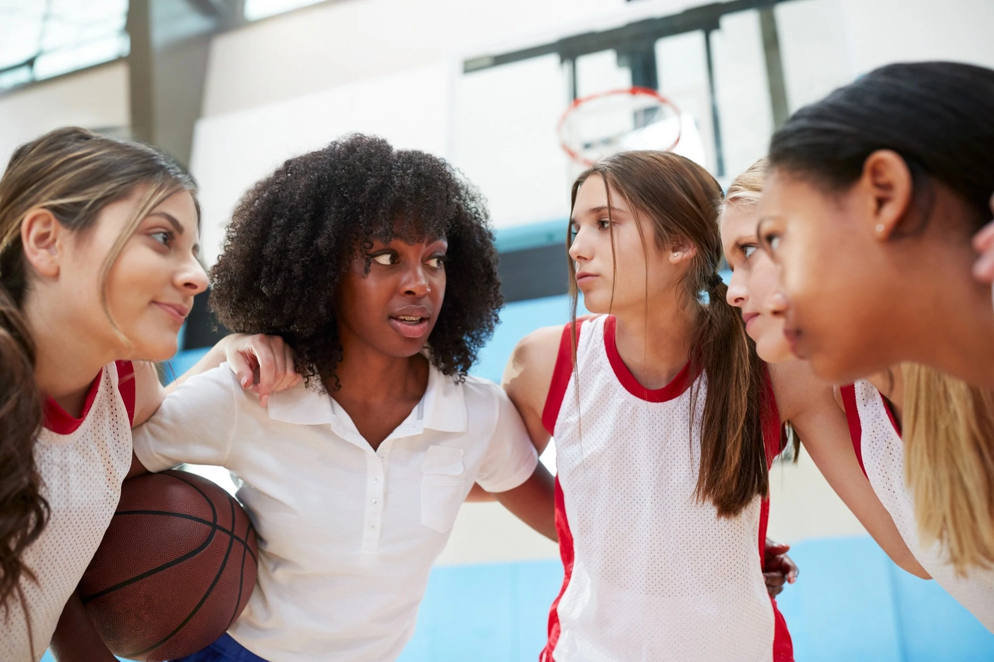 A group of female basketball players huddle together